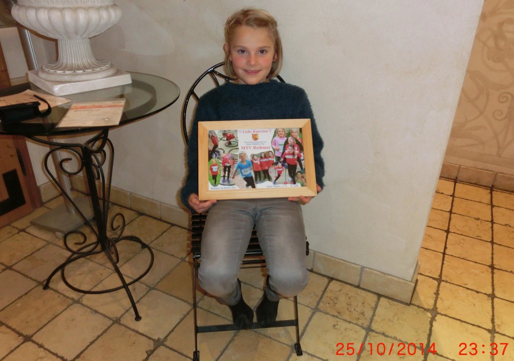 Katerina mit der Bildkolage, die sie als Erinnerung an ihre Laufzeit von ihren jungen und erwachsenen Mitläuferinnen und Mitläufern des MTV Rethmar bekommen hat.